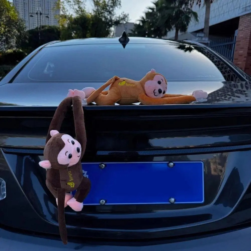 Brown monkey ornament hanging on a car boot with an orange one lying on the trunk