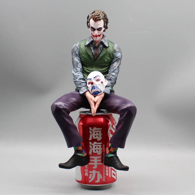 Front view of the seated Joker figure holding a mask